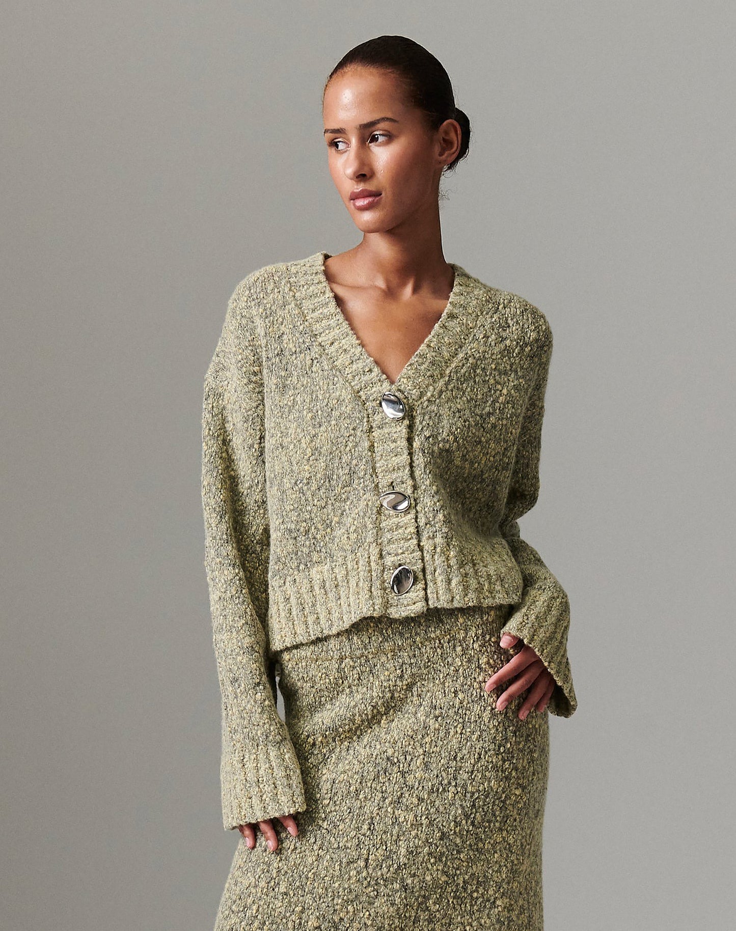 Close-up of model wearing DAY Birger ét Mikkelsen Conor Winter Melange Cardigan in capers green, showing oversized bauble buttons and textured knit.