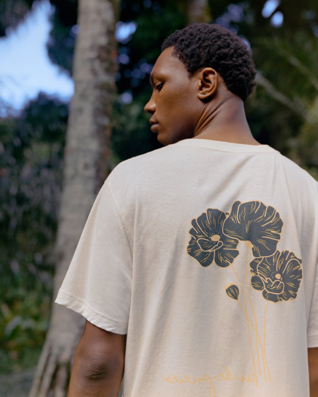 Person wearing a beige t-shirt with floral design outdoors