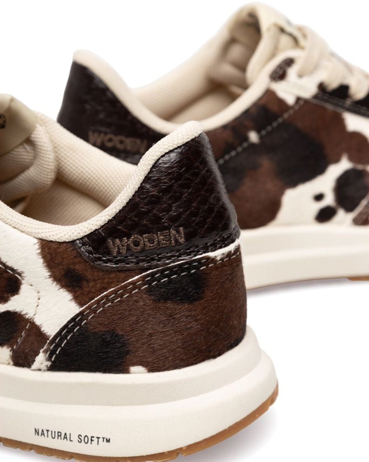 Cow print sneakers with 'Woden' branding on a white background