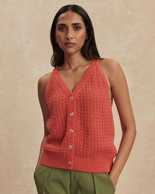 Woman wearing a red knitted vest against a beige background