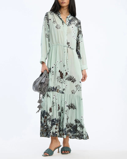 Woman wearing a floral dress holding a gray bag on a white background