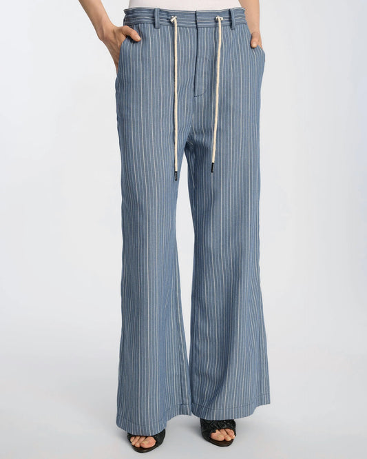 Woman wearing blue striped pants with a white top on a light gray background