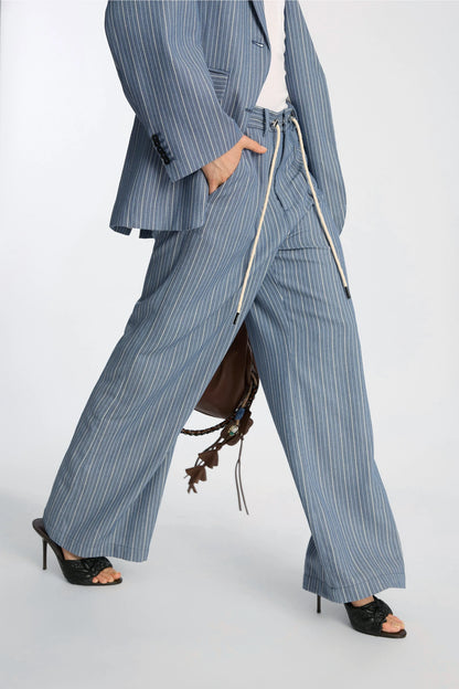 Person wearing a blue pinstripe suit with wide-leg pants on a white background