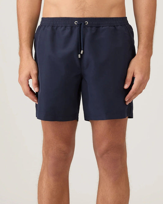 Person wearing navy swim shorts on a plain background