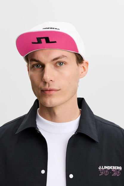 Person wearing a pink and white cap with a logo, black jacket, and white shirt on a white background